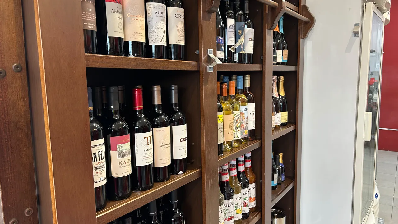 Estante de madeira com vinhos tintos, brancos e espumantes em quatro prateleiras